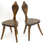 A pair of Arts & Crafts style spinning chairs of oak and elm construction with carved floral motifs,