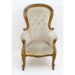 A late 19thC / early 20thC spoon back armchair with deep buttoned upholstery, scrolled arms and