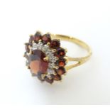 A 9ct gold ring set with central garnet bordered by diamonds bordered by further garnets. Ring