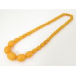 A bead necklace of graduated butterscotch amber coloured beads. Approx 20" long. The largest bead