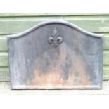 A mid 20thC cast iron fireback, with raised border and Fleur de Lys decoration, 25 1/2" wide