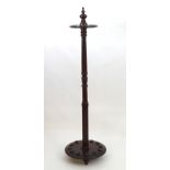 An early 20thC mahogany cue stand with a turned pole and pierced disk above a circular base. 64"