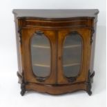 A Victorian rosewood bow fronted cabinet with a moulded top above a carved structure with oval glass