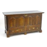 An 18thC oak mule chest with a moulded lid above four arched panels and two short drawers with brass