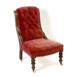 A Victorian mahogany slipper chair with a curved frame, deep buttoned upholstery and a sprung seat