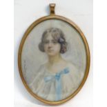 A 20thC watercolour portrait miniature depicting a seated young girl in a white dress with a blue