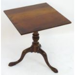 A George III mahogany tripod table with a squared top above a turned pedestal base with three