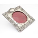 An Art Nouveau photograph frame with embossed silver surround with heart, scroll and floral detail