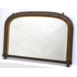 An early 20thC over mantle mirror with a curved top and blind fretwork carved surround with a gilt
