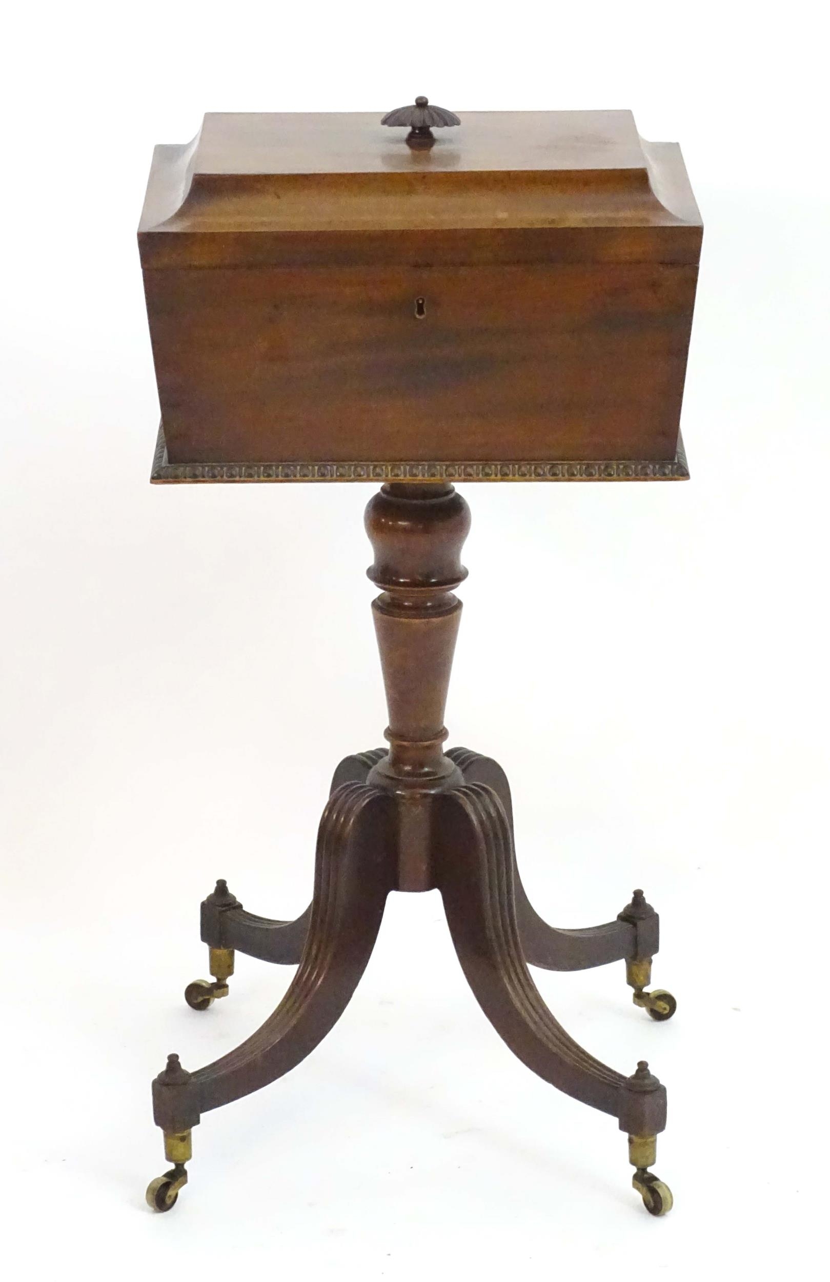 A Regency mahogany teapoy with a carved handle and sarcophagus shaped top, egg and dart mouldings