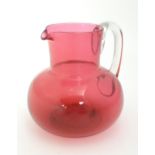 A late 19thC / early 20thC cranberry glass jug with clear glass handle. 6" high Please Note - we