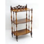 A rosewood whatnot / etagere with a carved pierced upstand, turned finials and tapering supports