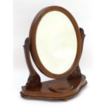 A Victorian mahogany toilet mirror with an oval mirror and shaped surrounds above a moulded base