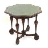 A 20thC centre table with a gold tooled leather top and moulded edge above five turned tapering
