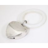 A white metal heart shaped rattle with teething ring. Approx. 3 1/2" long Please Note - we do not