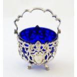 A Victorian silver sugar basket with pierced decoration, swing handle and blue glass liner,