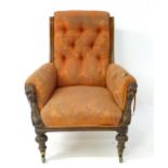 A mid 19thC mahogany library chair with scrolled sides, deep buttoned back and carved masks to the