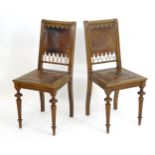 A pair of French early 20thC embossed leather hall chairs, having gilt metal studs above turned