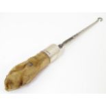 Taxidermy : A button hook, the handle formed as an otter paw with silver collar engraved North