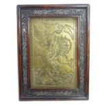 An Oriental brass plaque depicting a stylised dragon attacking a fish amongst waves. Within a carved
