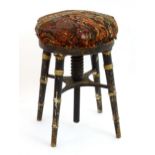 A 19thC ebonised and gilt piano stool with a circular upholstered top above four turned tapering