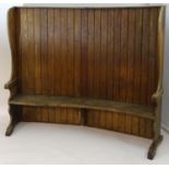 A 19thC tavern settle with an elm seat, planked bow back and shaped sides with scrolled armrests.