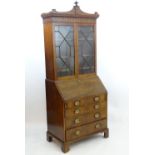 A late 18thC mahogany Georgian bureau bookcase with a carved pediment and moulded frieze above two