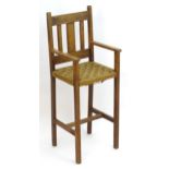 An early 20thC oak high chair / correction chair, with a slatted backrest above a seagrass woven