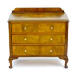 An early / mid 20thC walnut chest of drawers with a shaped upstand above three long drawers with