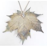 A pendant necklace, the white metal pendant formed as a stylised sycamore lead, on a silver chain