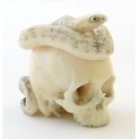 A late 19th / early 20thC Japanese carved netsuke modelled as a skull with coiled snake. Signed with