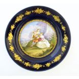 A Continental cabinet plate decorated with three figures in a landscape, the blue rim with gilt