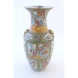 A Chinese famile rose vase with a flared rim and twin ring mask handles in relief, decorated with