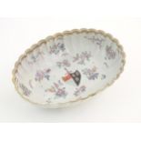 A Chinese export bowl of oval form with scalloped edge, decorated with flowers, foliage and armorial