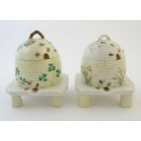 Two Belleek honey / preserve pots and covers formed as bee hives / skeps with bee, shamrock /