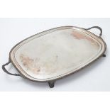 A silver plate tray with twin handles and four feet. 24 12" wide overall. Please Note - we do not