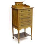 An early 20thC mahogany music cabinet with a shaped pierced upstand and five drawers with drop ends,
