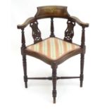 An early 20thC mahogany corner chair with pierced back splats above an upholstered seat, standing on