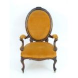A mid 19thC rosewood open armchair with an oval upholstered backrest, swept arms and raised on