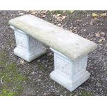 A late 20thC reconstituted stone garden bench, consisting of two pedestals supporting a