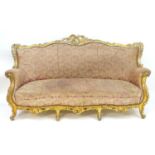An Italian giltwood three seat sofa with a carved and moulded gesso and wood frame, upholstered