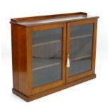 An early 20thC walnut glazed bookcase with an upstand above two glazed doors containing three