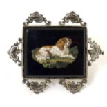 A 19thC Italian micromosiac brooch depicting a recumbent spaniel dog within a silver mount. In the