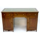 An early 20thC mahogany pedestal desk with a gold tooled leather top above three short drawers and