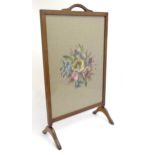 An early 20thC needlework fire screen with a mahogany frame and carrying handle to the top. 21" wide
