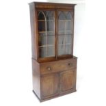 A Regency secretaire bookcase with a moulded cornice above two glazed doors with astragal glazed