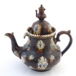 A large Victorian treacle glazed bargeware teapot with applied flower and bird decoration, the lid