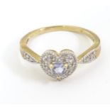 A 9ct gold ring set with central purple stone bordered by diamonds in a heart shaped setting,