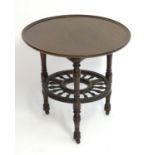 A late 19thC mahogany occasional table with a lazy Susan top and rounded under tier with turned