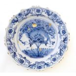 A Continental blue and white tin glazed charger with flowering tree decoration to centre and foliate